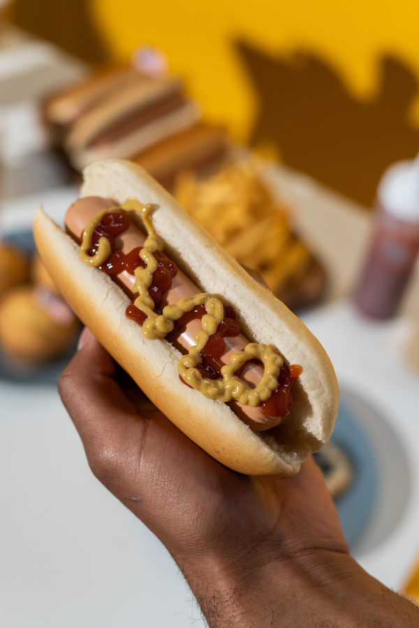 man holding hot dog with ketchup and mustard