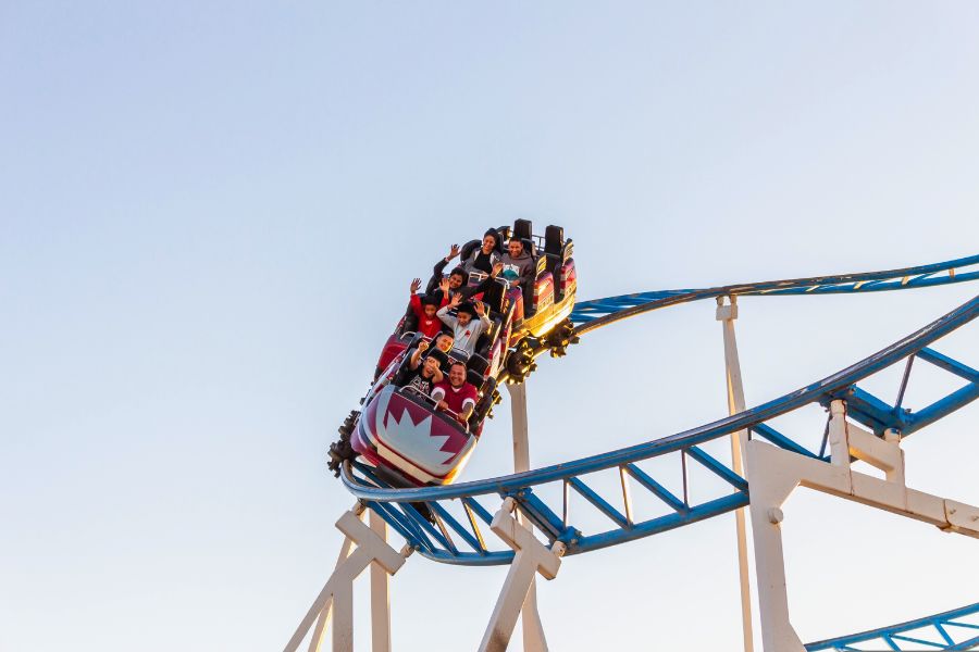 people riding a rollercoaster on a clear blue sky backdrop